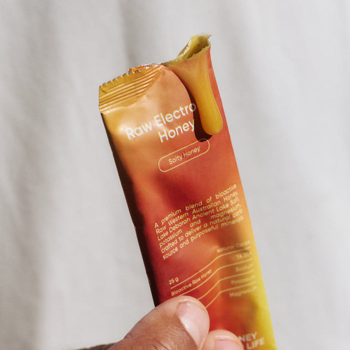 Hand holding an opened Sodii Raw Electrolyte Honey sachet, Salty Honey