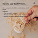 Hand holding a scoop of powdered Beef Protein Isolate - Chocolate Sea Salt - 450g by Switch Nutrition with usage instructions.