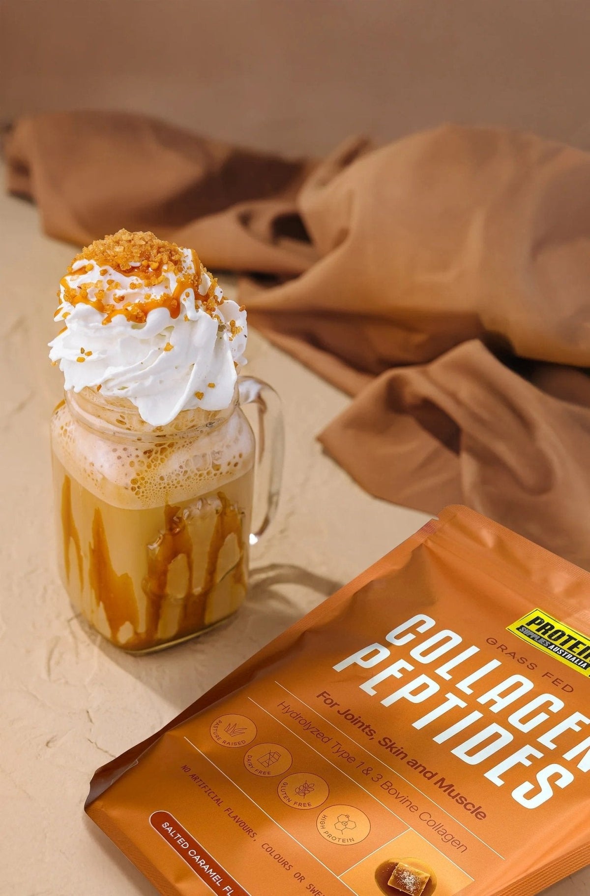 Glass mug with salted caramel drink topped with whipped cream beside Grass Fed Collagen Peptides - Salted Caramel - 500g by Protein Supplies Australia