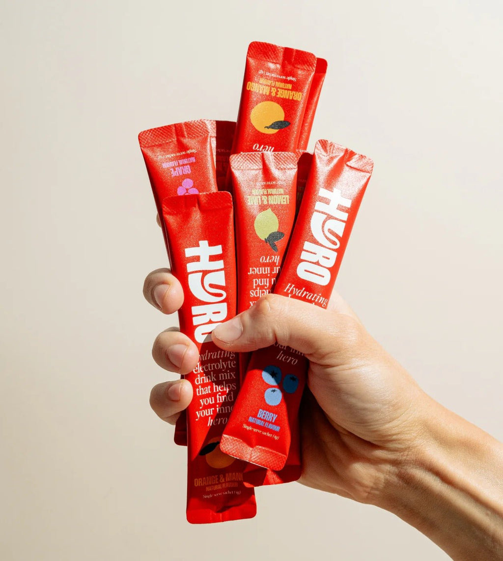 Hand holding multiple red Hyro Single Stick electrolyte drink mix sticks from Hyro brand collections.