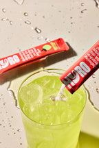 Hyro Single Stick electrolyte powder being poured into a glass of ice with green drink from Hyro functional low carb collection.