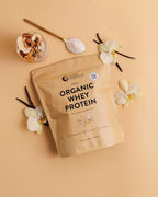 Organic Whey Protein - Vanilla - 750g pack by Nutra Organics with vanilla pods, flowers, and powder spoon on beige background