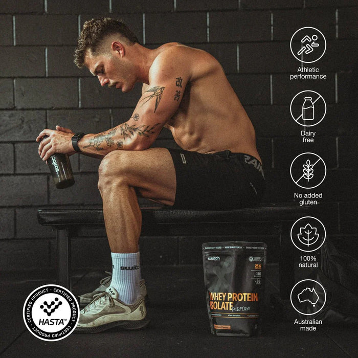A shirtless man sits on a gym bench with a shaker bottle and Perform Whey Protein Isolate - Vanilla 750g by Switch Nutrition at his feet. Icons showcase athletic performance, lactose-free, gluten-free, 100% natural, and Australian made features.