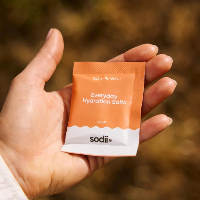 Hand holding a single orange and white sachet of Salty Mandarin - 30 Sachets by Sodii from the Electrolytes collection