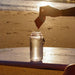 Salty Mandarin - 30 Sachets by Sodii being poured into water bottle on beach at sunset, part of Electrolytes collection
