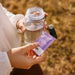 Person holding a sachet of Salty Passionfruit - 30 Sachets by Sodii and clear water bottle outdoors in natural light