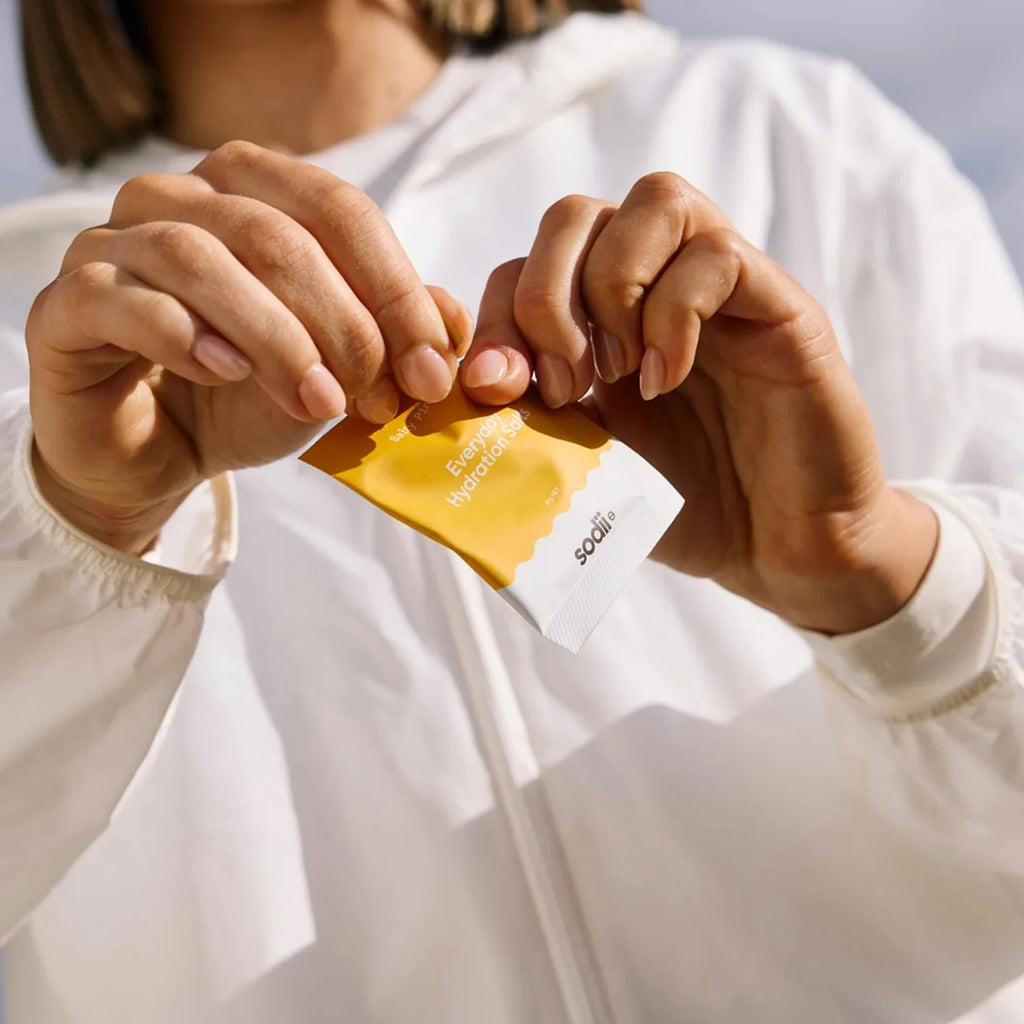 Person in white jacket opening Salty Pineapple - 30 Sachets by Sodii from new low carb electrolyte collection